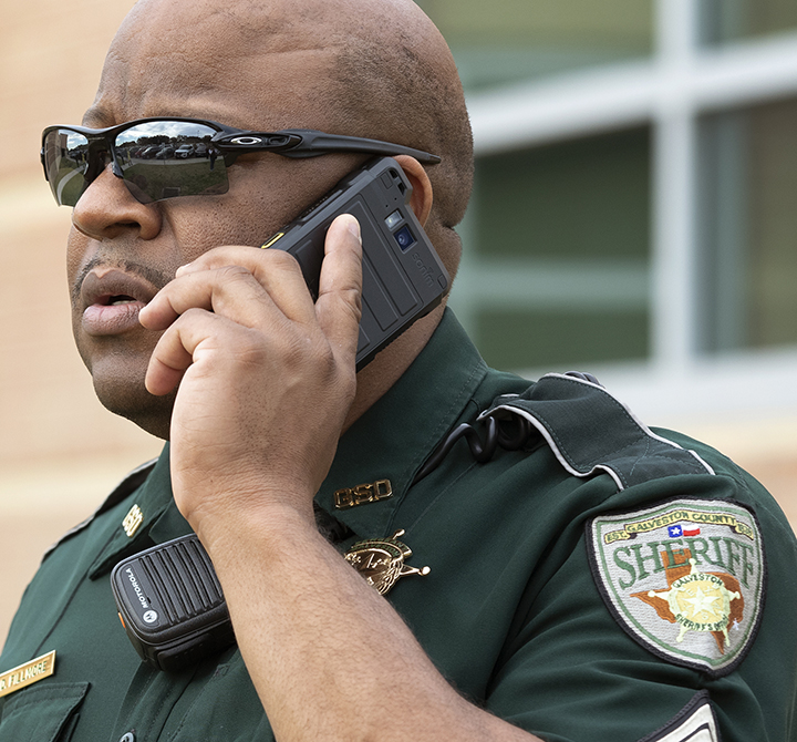 A school liaison officer stands outside Blocker Middle School in Texas City ISD. These Galveston County Sheriff deputies are equipped with FirstNet ready devices and the ISD is on FirstNet.