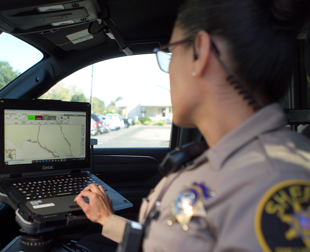 Female police officer using laptop in vehicle