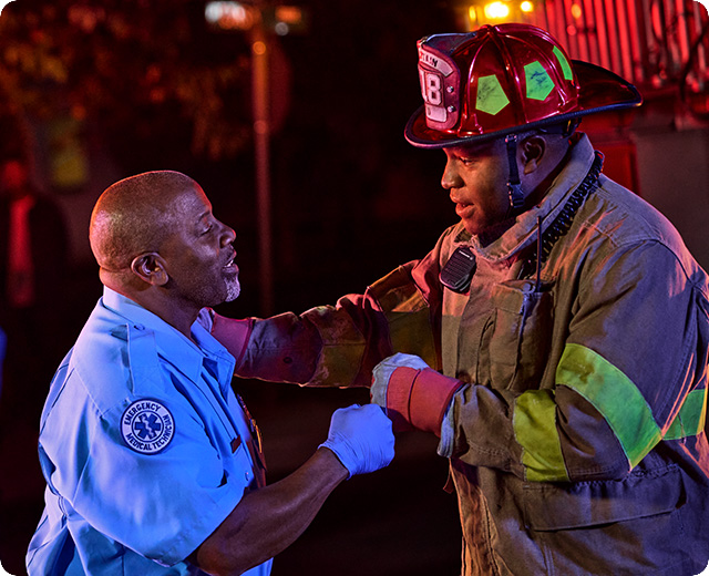 Emergency first responder and fire fighter fist bump on scene