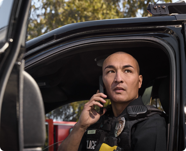 Police officer in cruiser talking on firstnet phone device 