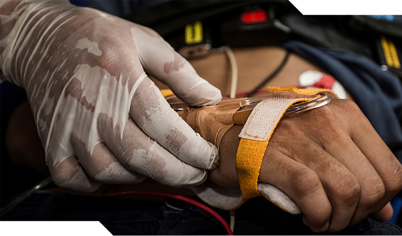 EMS worker holding an IV on the hand of a patient