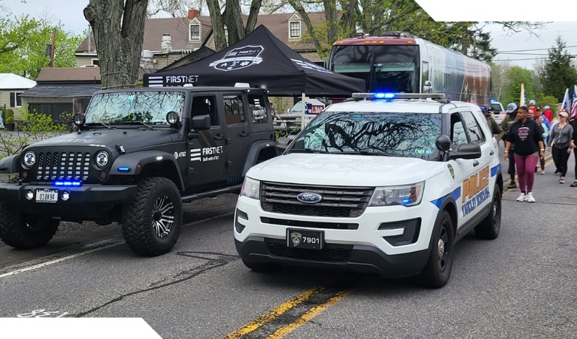 FirstNet connected vehicle and local police car parked in the street during 'Carry the Load' event.